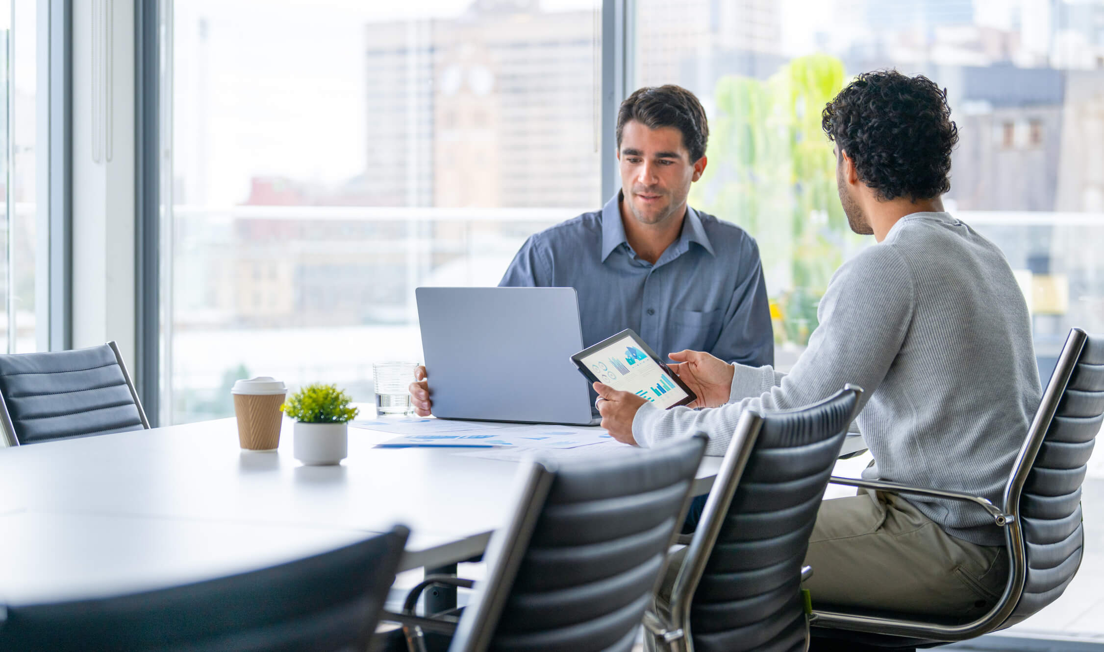 Two businessmen working on a digital tablet and laptop computer in the office